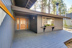 Eine Holzterrasse mit einem grauen Gebäude, das ein großes Fenster und eine Tür hat.