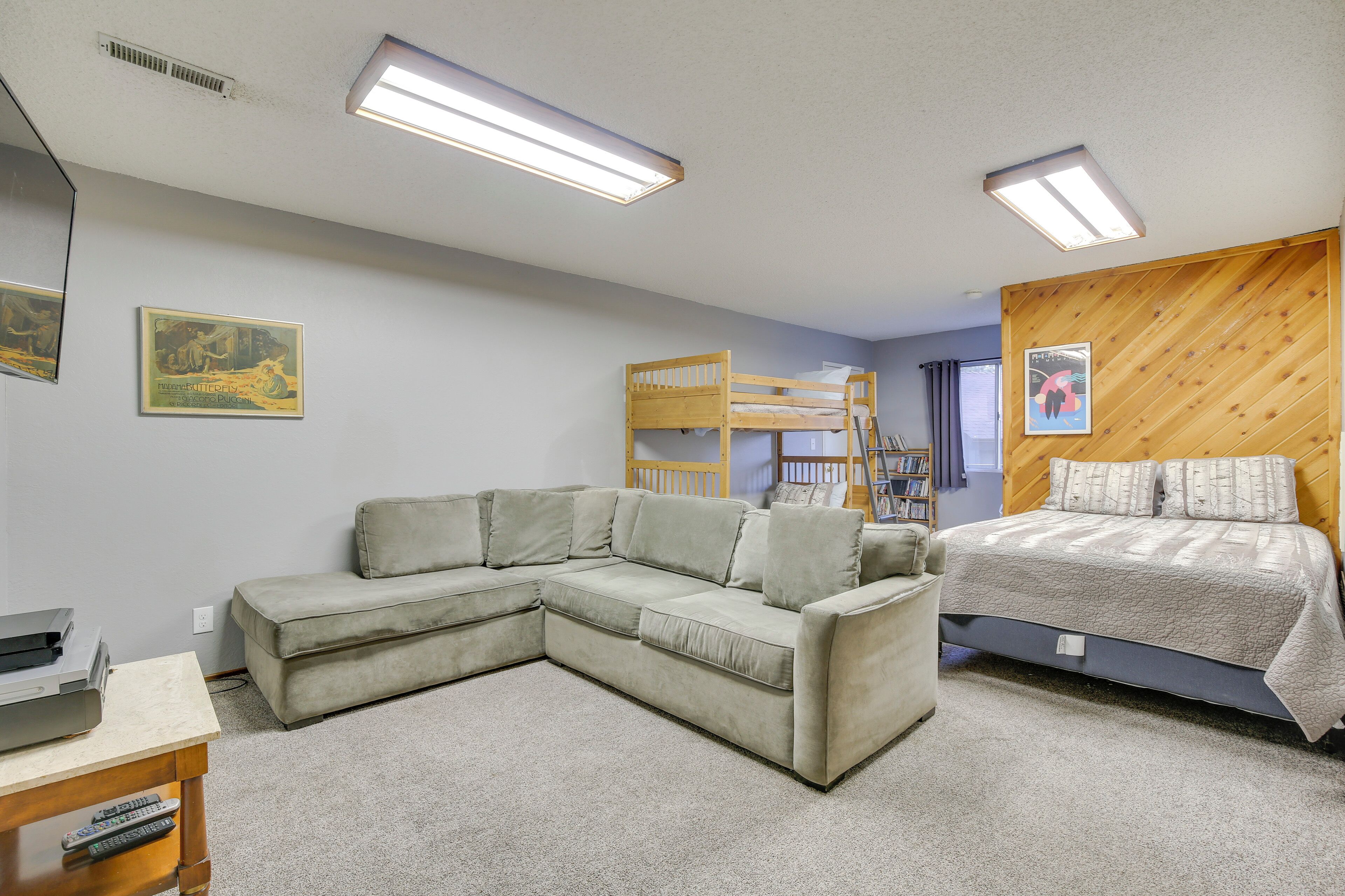 Una habitación con un sofá modular, una litera y una pequeña mesa con un control remoto.