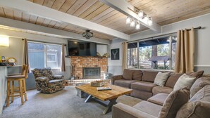 Un salon chaleureux avec une cheminée, un plafond en bois et une grande fenêtre.