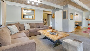 Un salon moderne avec un canapé d’angle, une table basse en bois et un grand miroir.