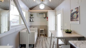 A compact kitchen with a wooden ceiling, a small seating area, and a dining table. - The Merlot Bungalow Defiance Tiny Home on Trail (Defiance)