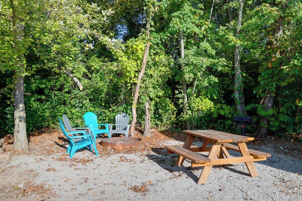 Un'area picnic con tavolo di legno e sedie blu in una zona boschiva.