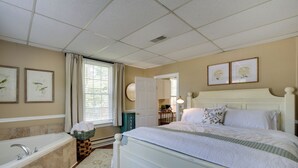 A bedroom with a large bed, a bathtub, and a window with curtains. - 'the Cabernet Cabin' Defiance Home on Katy Trail! (Defiance)