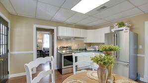 A kitchen with white cabinets, a stainless steel refrigerator, and a dining table with placemats and vases. - 'the Cabernet Cabin' Defiance Home on Katy Trail! (Defiance)