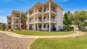 A multi-story residential building with balconies, a well-maintained lawn, and a clear sky. - Pool Access & Patio! Resort-style St George Condo (St. George)