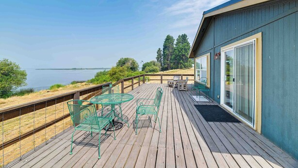 A wooden deck with a table and chairs, overlooking a body of water. - Lakefront Chiloquin Home w/ Scenic Deck! (Chiloquin)