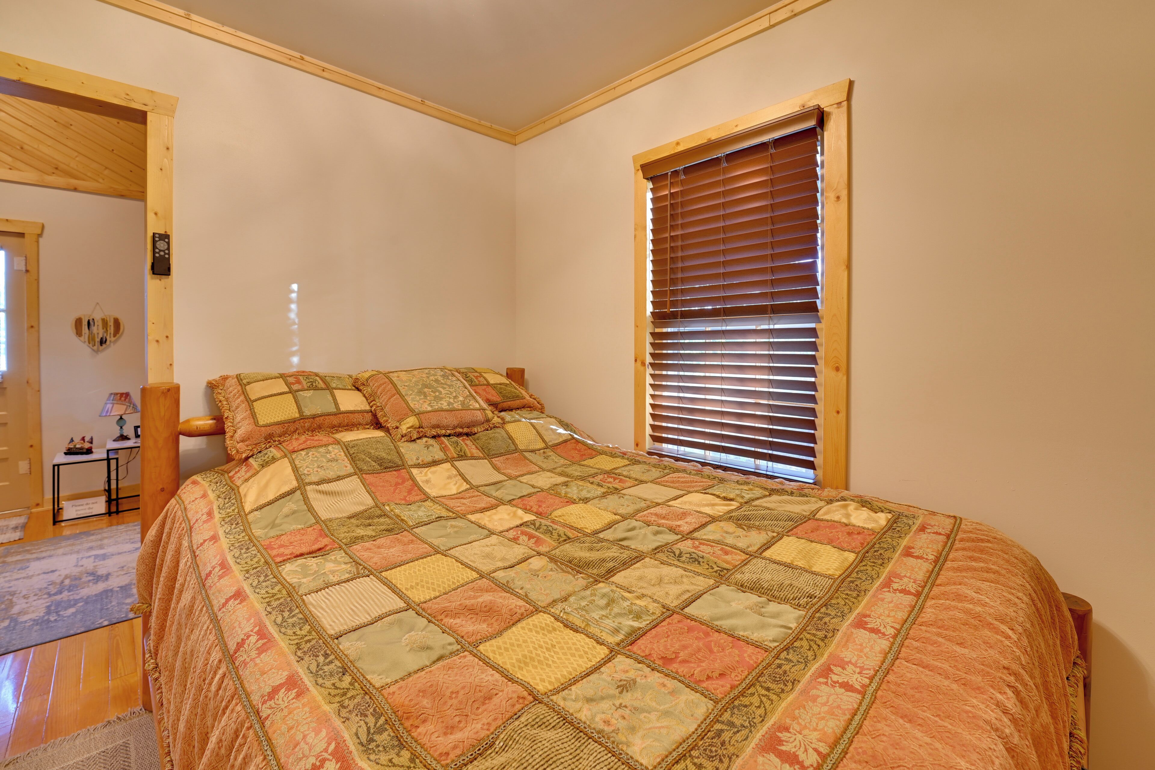Un dormitorio con una cama grande, una ventana con persianas, un cabecero de madera y una mesita de noche con lámpara.