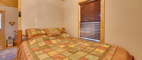 Un dormitorio con una cama grande, una ventana con persianas, un cabecero de madera y una mesita de noche con lámpara.