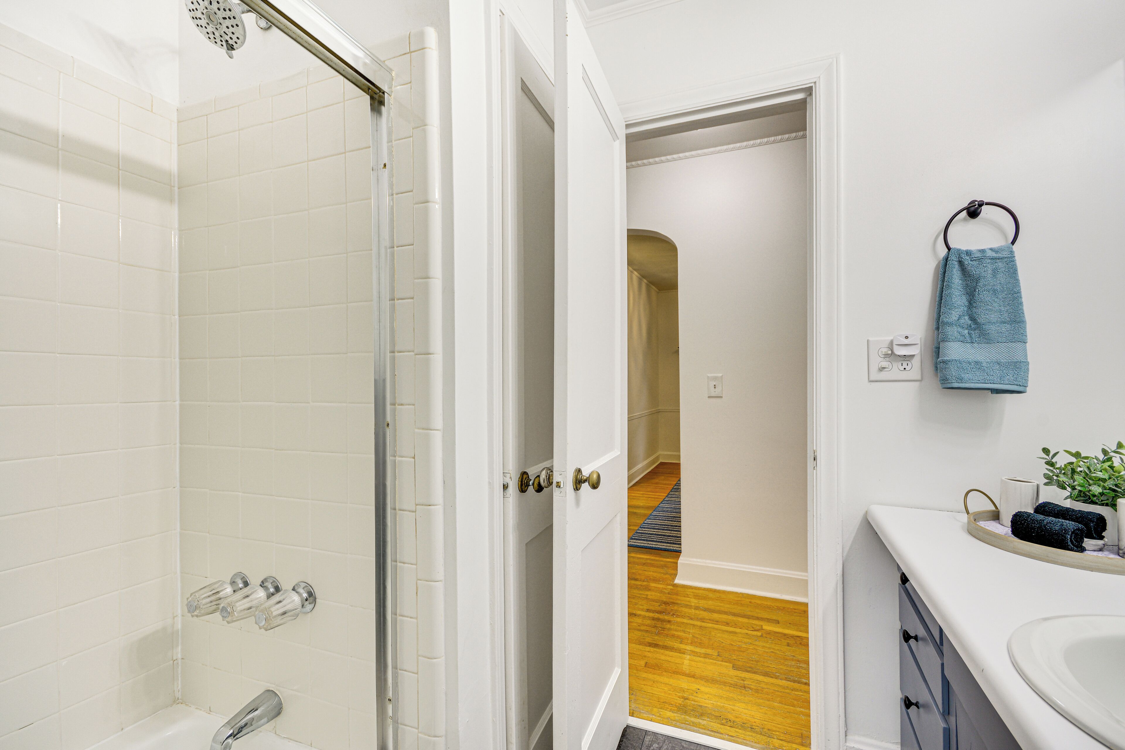 A bathroom with a shower, a sink, and a towel rack.