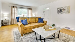 A living room with a sofa, a coffee table, a lamp, and a painting on the wall. - 'dogwood Cottage' w/ Fireplace: 1 Mi to University (High Point)