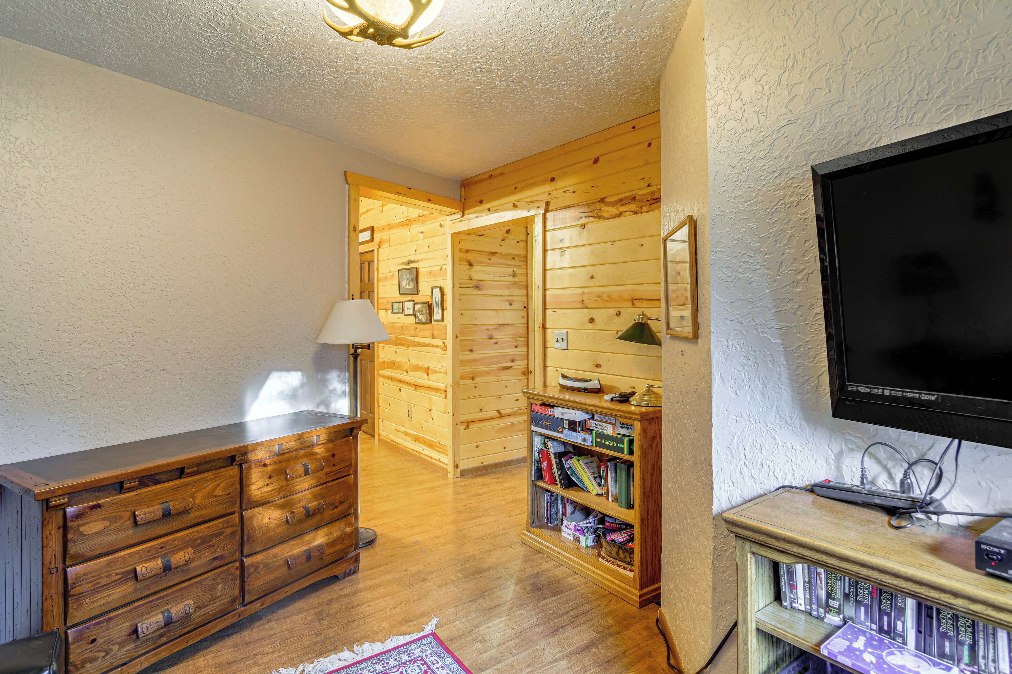 A wooden interior with a TV, bookshelf, and a dresser.