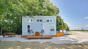A small, light blue cabin with a deck, two chairs, and a table. - 'the Chardonnay Chalet' Defiance Studio Trail! (Defiance)