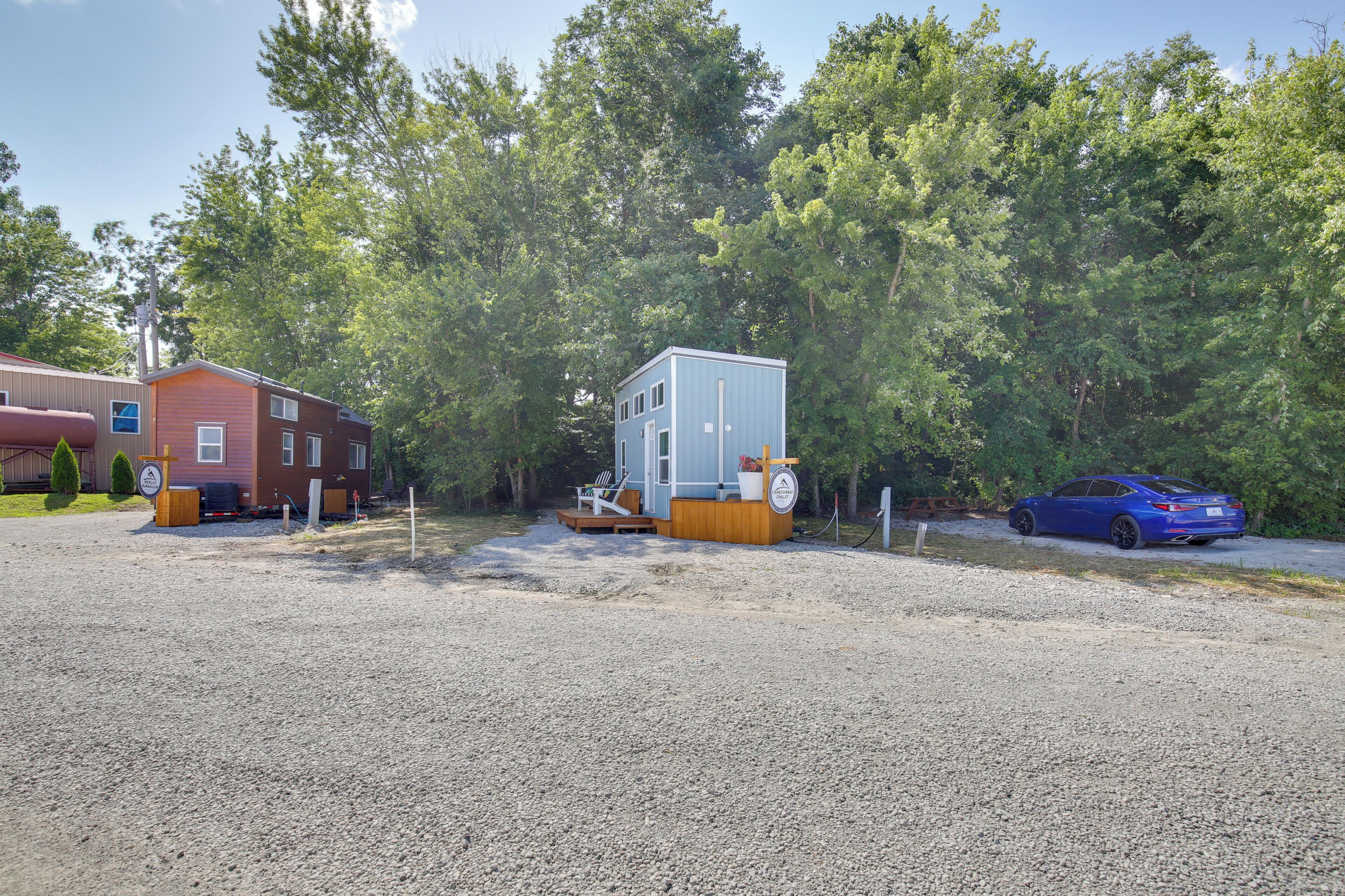 A gravel parking area with a small blue cabin and a red building.