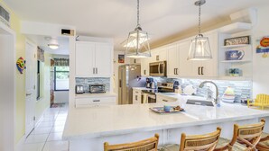 A spacious kitchen with white cabinets, a large island with bar stools, and pendant lighting. - Key Largo Condo - Community Pool, Marina & Beach! (Key Largo)