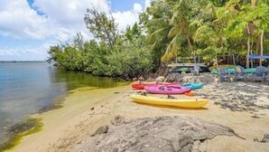 A beach with kayaks, a palm tree, and a clear sky. - Key Largo Condo - Community Pool, Marina & Beach! (Key Largo)