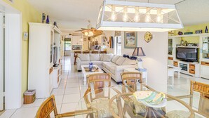 A spacious living room with a dining area, a kitchen in the background, and a TV in the corner. - Key Largo Condo - Community Pool, Marina & Beach! (Key Largo)