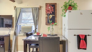 Une cuisine compacte comprenant un coin repas, un réfrigérateur, un téléviseur et une fenêtre avec des rideaux.