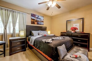 Un dormitorio con cama, mesitas de noche, cómoda, ventilador de techo y un cuadro de la Torre Eiffel.