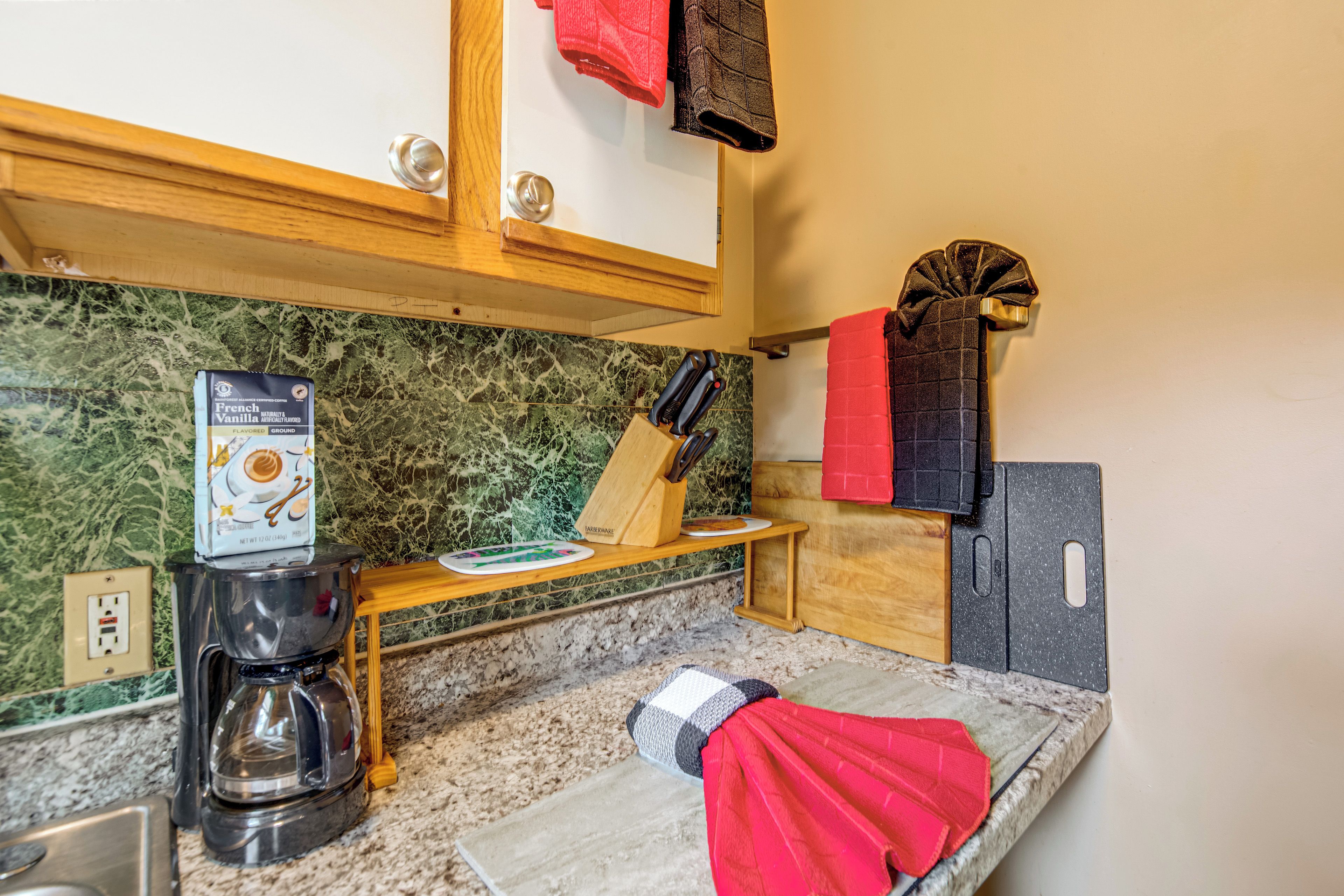 A kitchen with a coffee maker, a knife block, and a red towel hanging on the wall.