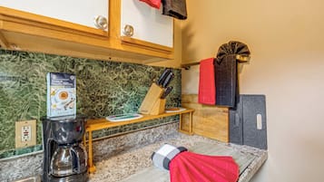 A kitchen with a coffee maker, a knife block, and a red towel hanging on the wall.