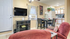 Un espace de vie compact comprenant un coin repas, un téléviseur fixé au mur, un ventilateur de plafond et un réfrigérateur.