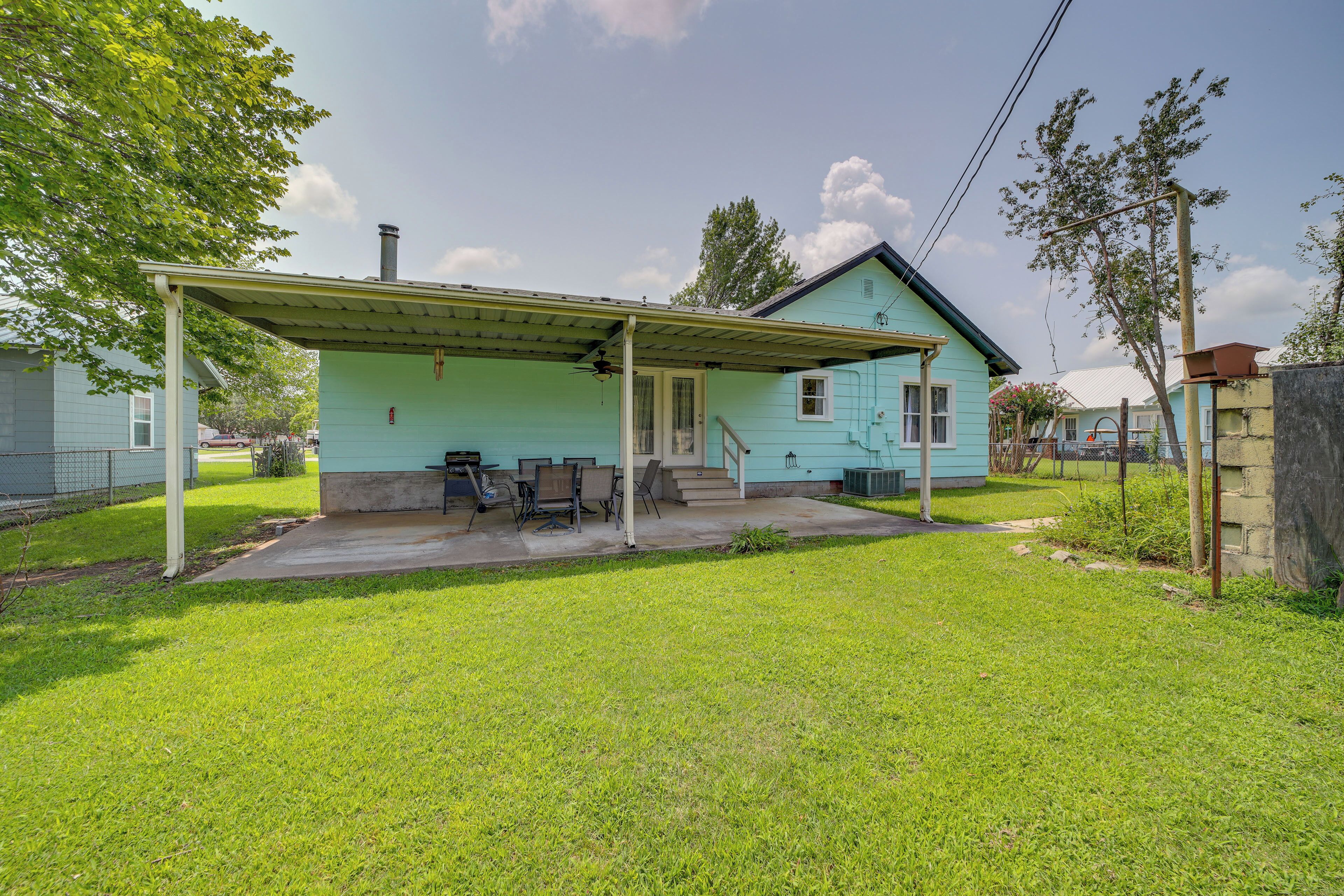 A light blue house with a covered patio, a lawn, and a fence.
