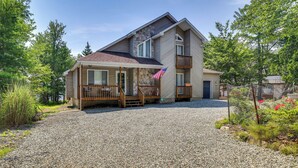 A two-story house with a stone facade, a wooden deck, and a gravel driveway. - Private Hot Tub: Lakefront Poconos Home! (Pocono Summit)