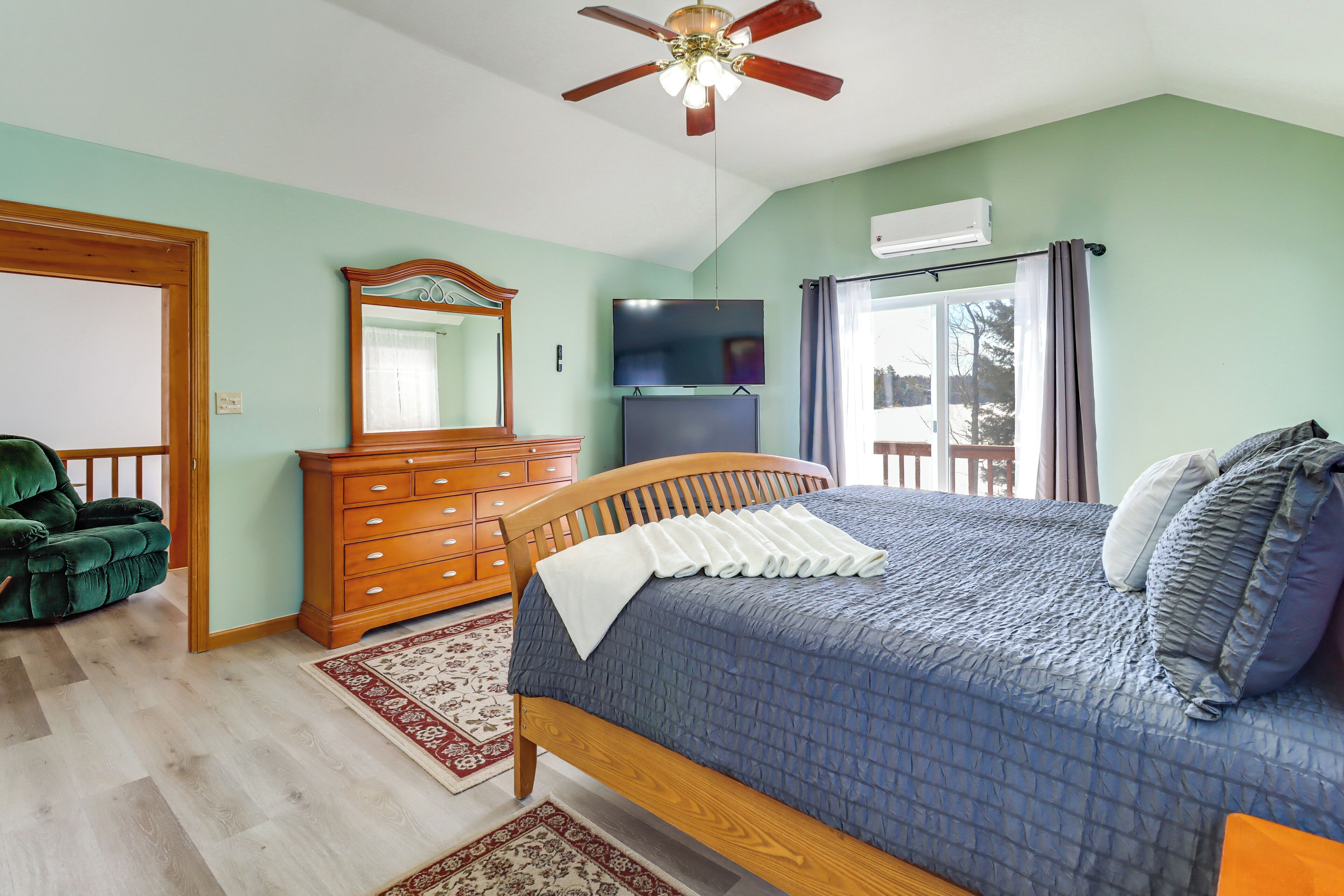 A bedroom with a bed, dresser, mirror, and ceiling fan.