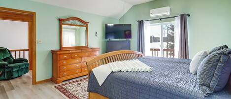 A bedroom with a bed, dresser, mirror, and ceiling fan.
