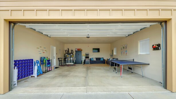 A garage with a ping pong table, a blue playpen, and a blue cabinet.