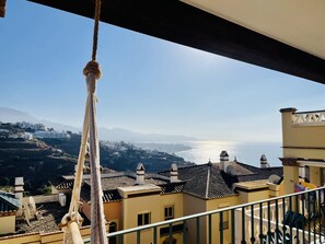 A balcony with a view of a coastal town, including buildings and a body of water. - Apartment Altos de Tamango in Nerja (Nerja)