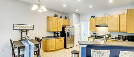Una cocina moderna con armarios de madera, un refrigerador de acero inoxidable y un comedor con mesa y sillas.
