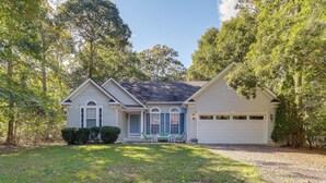 A two-story house with a front porch, a garage, and a well-maintained lawn. - Dog-friendly Family Retreat Near Chincoteague Bay! (Greenbackville)