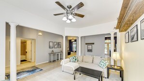 A spacious living room with a sectional sofa, a coffee table, and a ceiling fan. There is a hallway leading to another room and a door to the left. - Dog-friendly Family Retreat Near Chincoteague Bay! (Greenbackville)