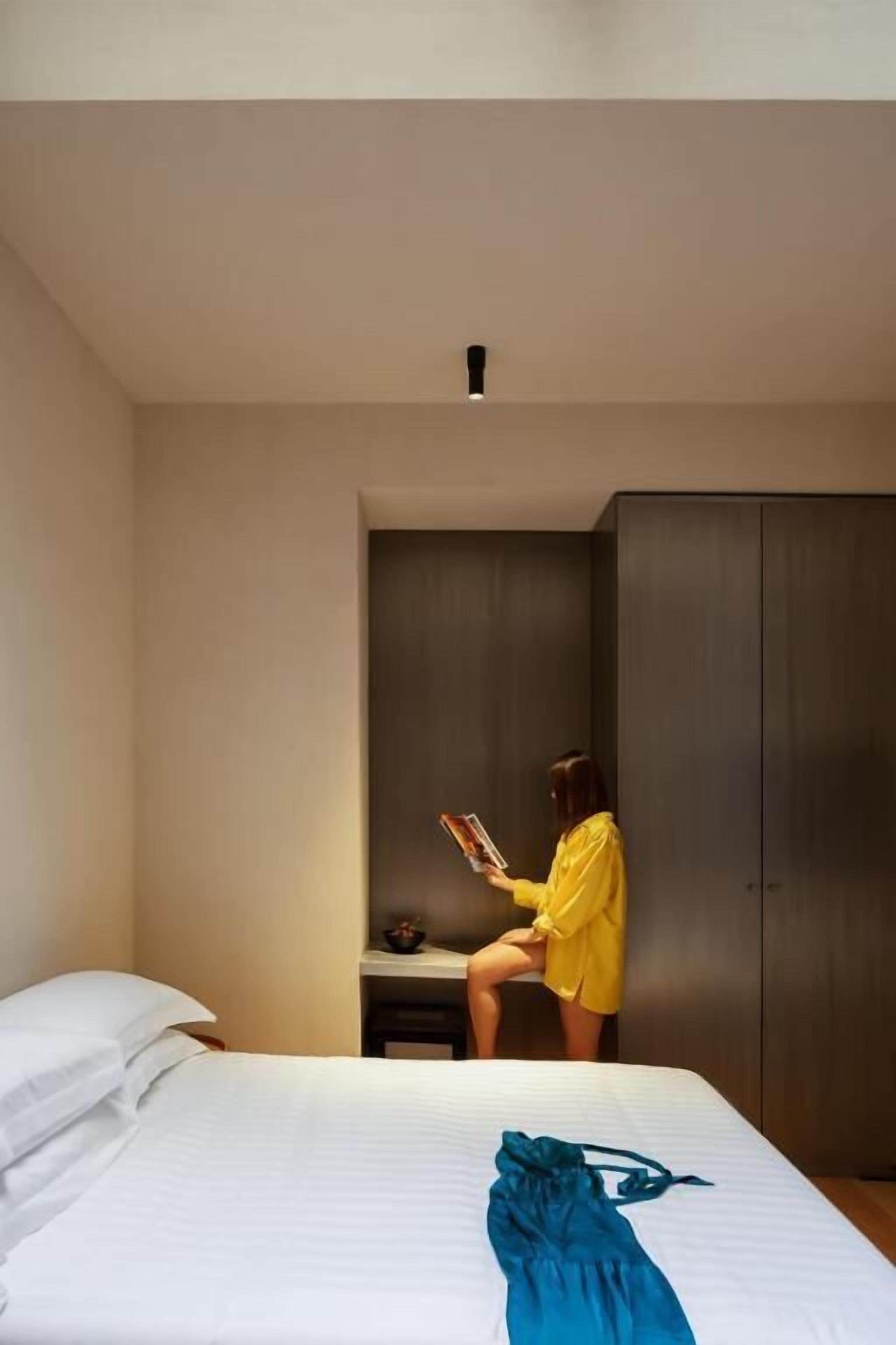 Una camera d'albergo con un letto, una scrivania e un armadio.