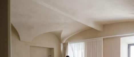 A bedroom with a large bed, a nightstand, and a window with curtains.