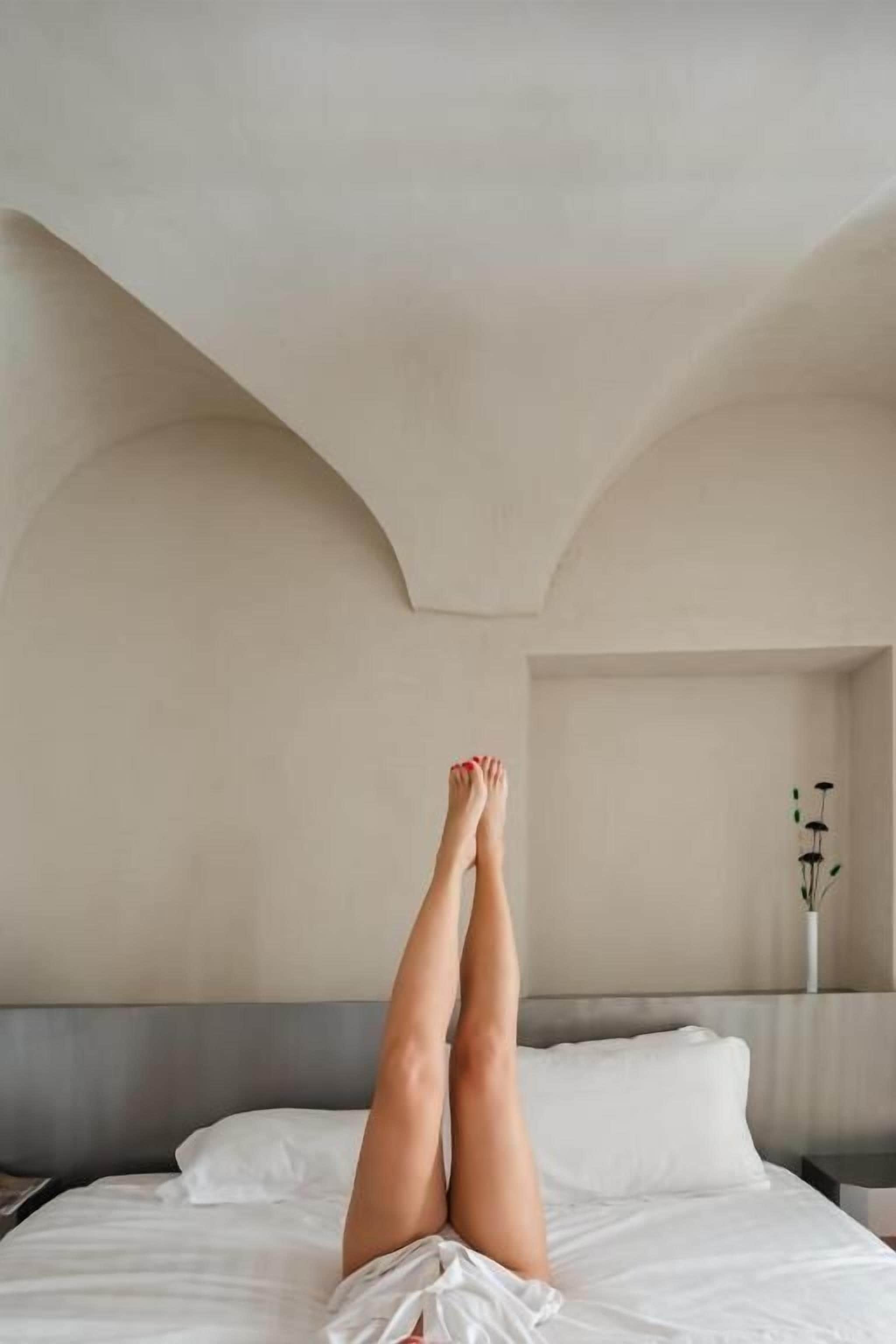Una camera d'hotel con un letto, un comodino e un vaso con fiori sul comodino.