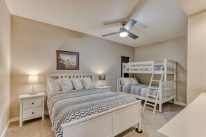A bedroom with a single bed, a bunk bed, a nightstand with a lamp, a ceiling fan, and a framed picture on the wall. - Sand & Sea (110) Pacific Nook: Oceanview & Pool (Seaside)