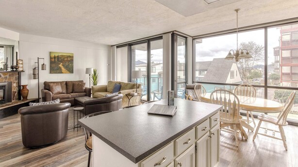 Una sala de estar moderna con chimenea, un comedor con mesa y sillas, y grandes ventanales con vistas a la ciudad.