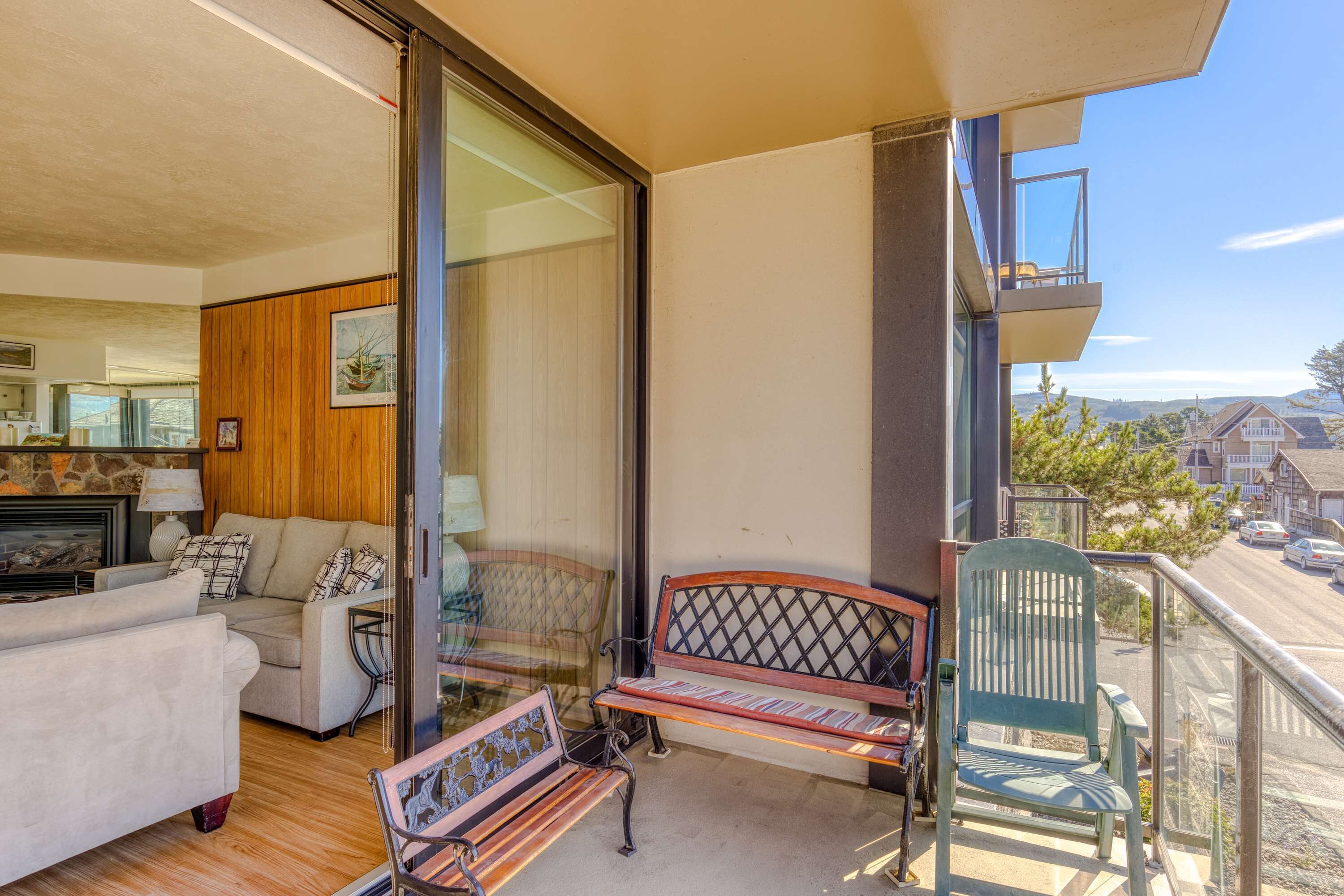 A balcony with a wooden bench, a green chair, and a sofa.