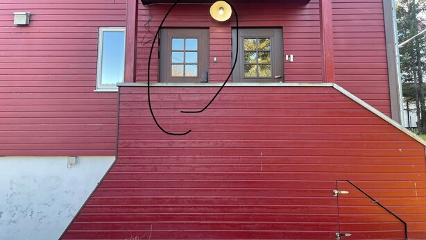 A red building with a balcony, a door, and a window. - Arctic Paradise - 4 Bedroom Apartment in Tromso (Tromsø)