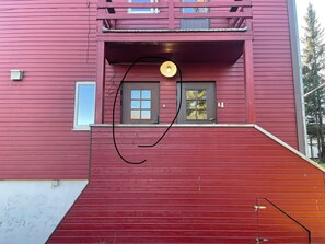A red building with a balcony, a door, and a window. - Arctic Paradise - 4 Bedroom Apartment in Tromso (Tromsø)