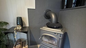 A modern kitchen with a built-in wood stove, a glass cabinet with decorative items, and a potted plant. - Arctic Paradise - 4 Bedroom Apartment in Tromso (Tromsø)
