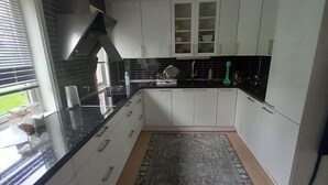 A modern kitchen with white cabinets, a black countertop, and a patterned rug. - Arctic Paradise - 4 Bedroom Apartment in Tromso (Tromsø)