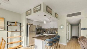 Een moderne keuken met een centraal eiland, barstoelen en een eethoek.