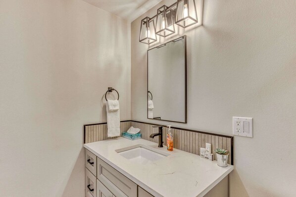 A modern bathroom with a white sink, a large mirror, and a towel rack.