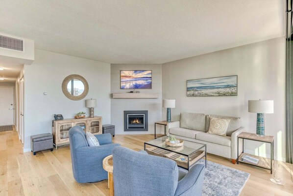 A modern living room with a fireplace, a sofa, a coffee table, and a lamp.