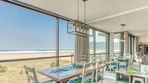 Un comedor con vista a la playa, ventanas amplias y una lámpara colgante.