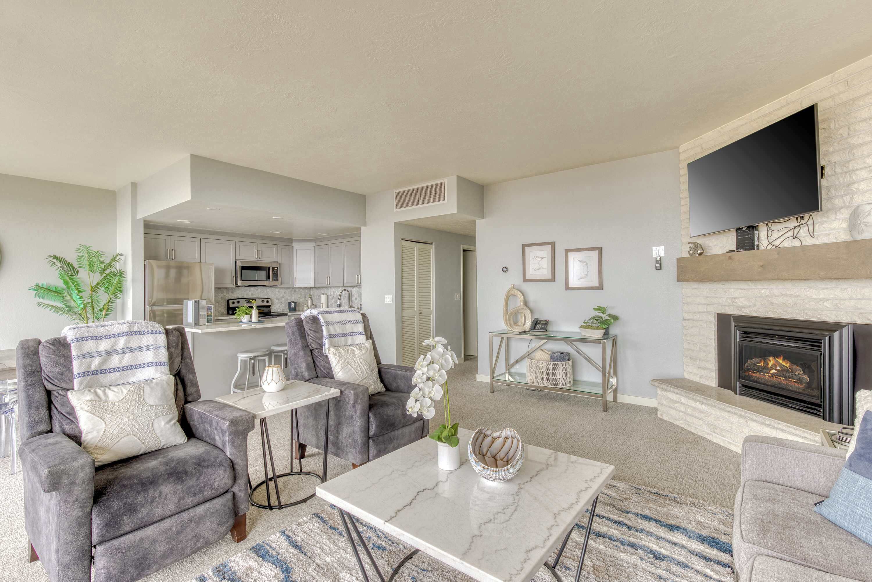 A modern living room with grey sofas, a marble coffee table, and a fireplace.
