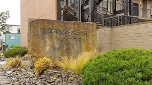Une enseigne indiquant l’adresse des appartements Sand & Sea Condominiums, située au 475, avenue S. Prom, et entourée d’un espace paysager agrémenté de rochers et d’arbustes.
